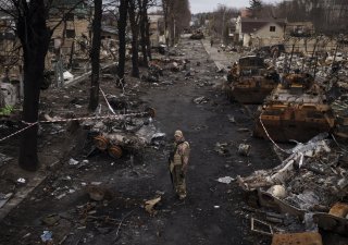 Ukrajinský muž stoj na ulici poseté zničenými ruskými tanky v městě Buča, kde se Rusové podle očitých svědků i západních médií a vlád dopustili zabíjení civilistů a válečných zločinů, 6. dubna 2022.