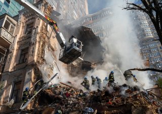 Záchranáři uklízejí a prohledávají trosky domu po útoku ruského dronu na Kyjev v říjnu 2022.