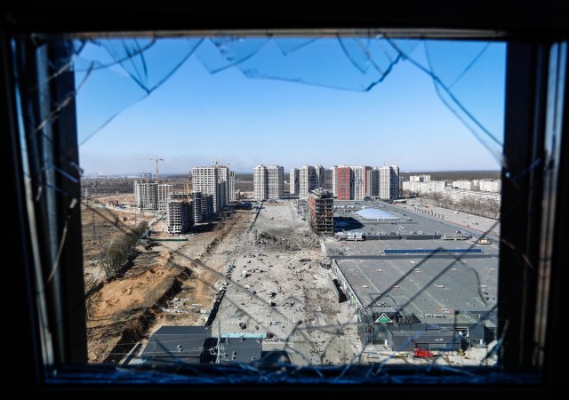 Výhled z rozbitého okna na ruským útokem zničené nákupní centrum v Kyjevě, 21. března.