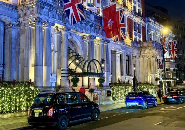 Večerní pohled na fasádu Mandarin Oriental Hyde Park. Vlajky, světla a Londýn