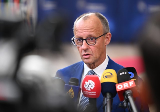 Německý kancléř Friedrich Merz hovoří s novináři při příjezdu do budovy Evropské rady v Bruselu na summit EU ve čtvrtek 15. října 2026.
