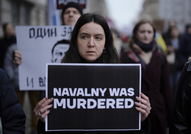 Lidé protestující před ruskou ambasádou v Berlíně. Žena drží transparent s výrokem, že Navalnyj byl zavražděn.