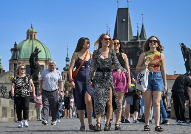 Turistiky se procházejí po Karlově mostě v Praze
