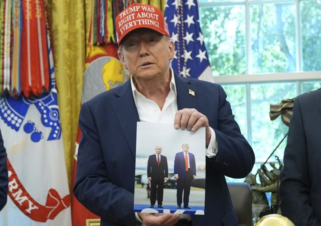 Americký prezident Donald Trump ukazuje fotografii s Putinem