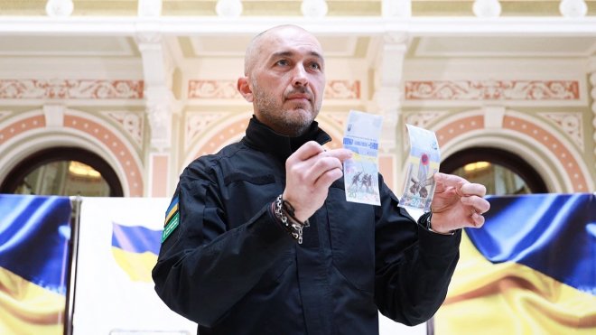 Guvernér centrální banky Andrij Pyšnyj ukazuje rub a líc speciální bankovky vydané k výročí ruské invaze.