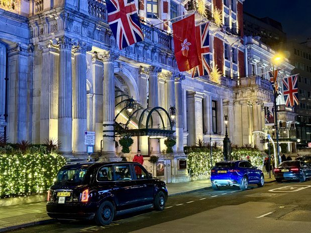 Večerní pohled na fasádu Mandarin Oriental Hyde Park. Vlajky, světla a Londýn