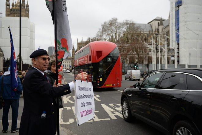 Britský penzista George Cowey mává na vládní auta vjíždějící do areálu parlamentu v Londýně, který 20. března 2019 jednal o otázkách spojených s brexitem. Nápis na ceduli vyzývá k "navrácení britské suverenity".