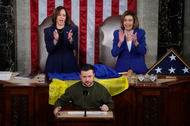 Ukrajinský prezident Volodymyr Zelenskyj v americkém Kongresu 21. prosince 2022. Před viceprezidentkou Kamalou Harrisovou a šéfkou americké Sněmovny reprezentantů Nancy Pelosiovou leží ukrajinská vlajka s podpisy vojáků z osvobozeného ukrajinského města Bachmut.