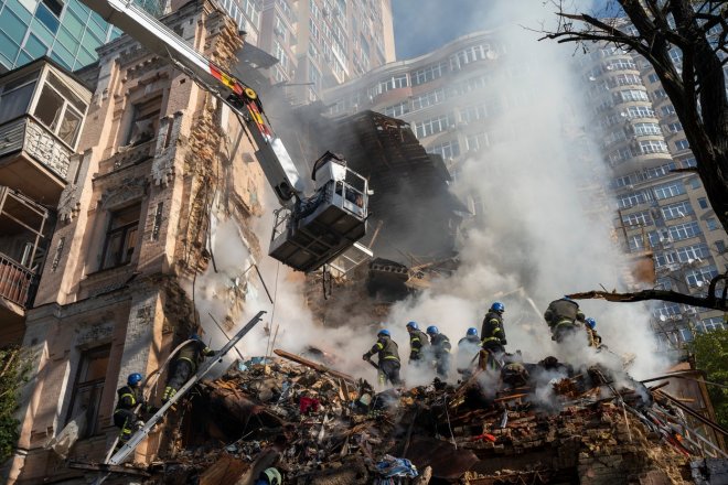 Záchranáři uklízejí a prohledávají trosky domu po útoku ruského dronu na Kyjev v říjnu 2022.