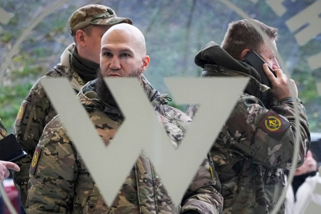 Návštěvníci ve vojenské kamufláži stojí u vchodu do „PMC Wagnerova centra“, které je spojeno s podnikatelem a zakladatelem soukromé vojenské skupiny Wagner Jevgenij Prigožin, během oficiálního otevření kancelářského bloku během Dne národní jednoty v St. Petersburg, Rusko, 4. listopadu 2022.