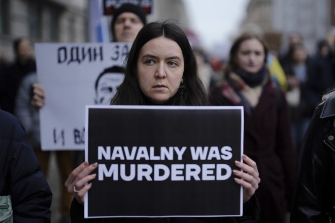 Lidé protestující před ruskou ambasádou v Berlíně. Žena drží transparent s výrokem, že Navalnyj byl zavražděn.