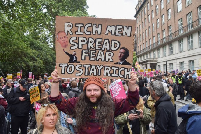 Demonstrant drží transparent zobrazující Farage, Muska a Zuckerberga během pochodu proti rasismu a fašismu a na podporu migrantů na Russell Square. Zatímco krajně pravicoví demonstranti v čele s Tommym Robinsonem pořádají vlastní shromáždění před Downing Street pod názvem „Unite The Kingdom“.
