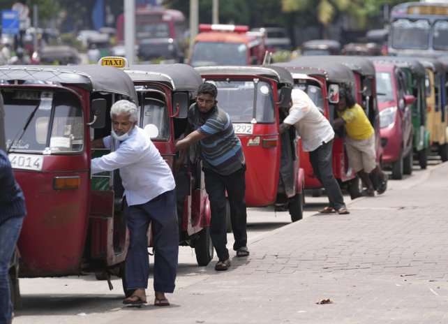 Srílanští řidiči tlačí své rikši k čerpací stanici