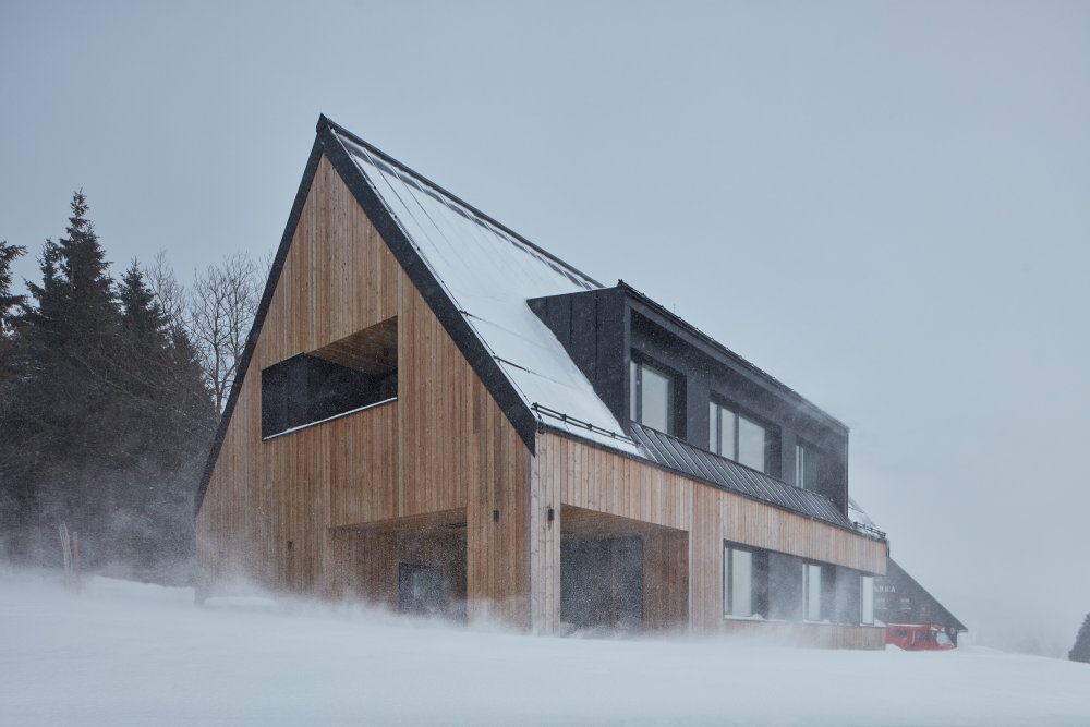 Architekti měli pro rodinu s dvěma dětmi navhnout chatu, která zapadne do krajiny, bude respektovat místní architekturu a zároveň i působit moderním dojmem.