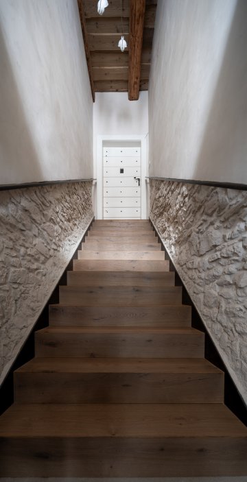 Schodiště do patra bylo ve velmi špatném stavu. I tady architekti využili obnažených kamenných stěn a strukturu zvýraznili podsvětleným madlem zábradlí. 
