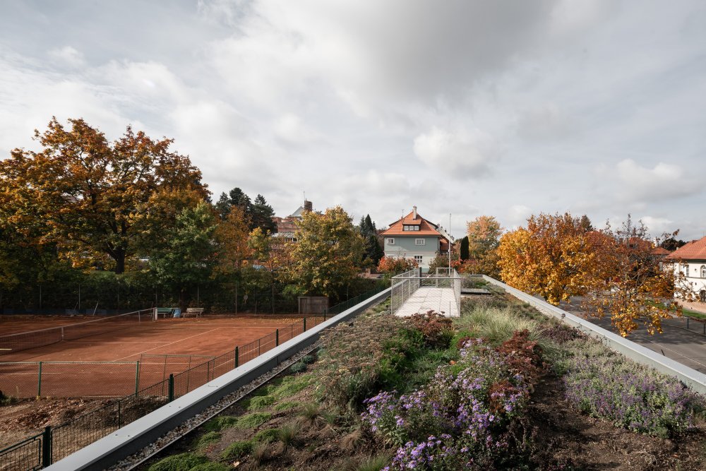 Dřevostavba, která klubovnu tvoří je záměrně lehká a vystavěná na sloupech jako zahradní pavilon uprostřed parku. Svým výrazem evokuje lázeňské altány a kolonády spojené s relaxací a klidem. 