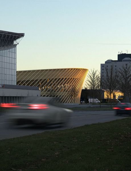 Hala je navržena jako dřevěný pavilon s výraznou fasádou a zakřivenou střechou.
