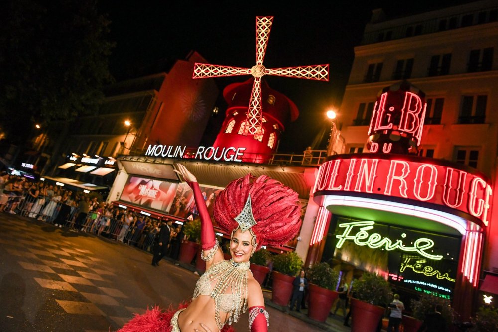 Lopatky červeného větrného mlýna na kabaretu Moulin Rouge v Paříži se roztočily ve čtvrtek večer. Událost oslavily desítky slavnostně oděných tanečnic před objektem tancem kankánu.