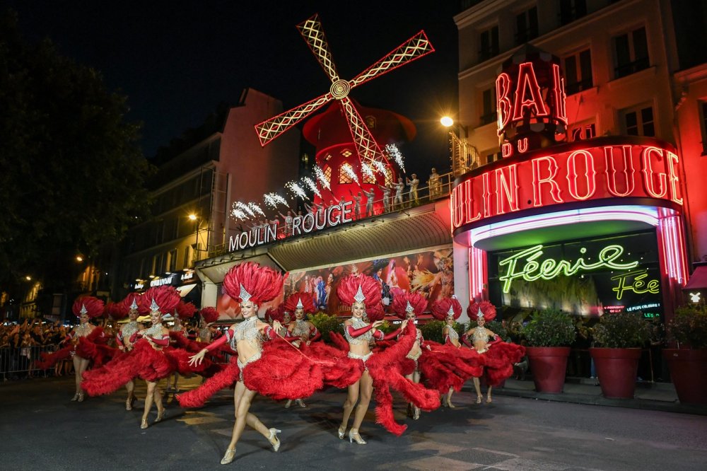 Lopatky červeného větrného mlýna na kabaretu Moulin Rouge v Paříži se roztočily ve čtvrtek večer. Událost oslavily desítky slavnostně oděných tanečnic před objektem tancem kankánu.