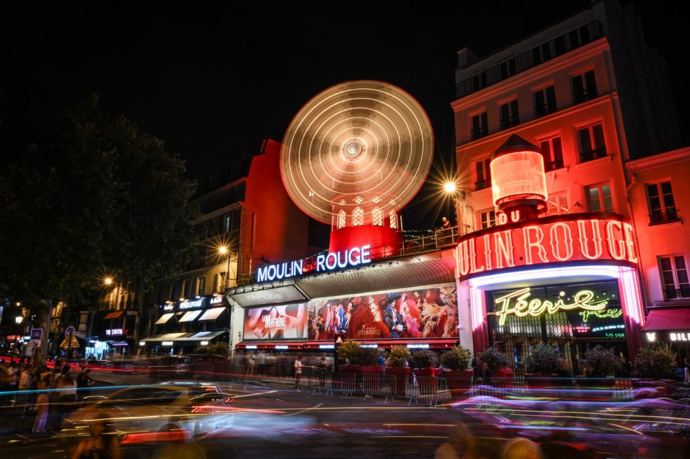 Lopatky červeného větrného mlýna na kabaretu Moulin Rouge v Paříži se roztočily ve čtvrtek večer. Událost oslavily desítky slavnostně oděných tanečnic před objektem tancem kankánu.