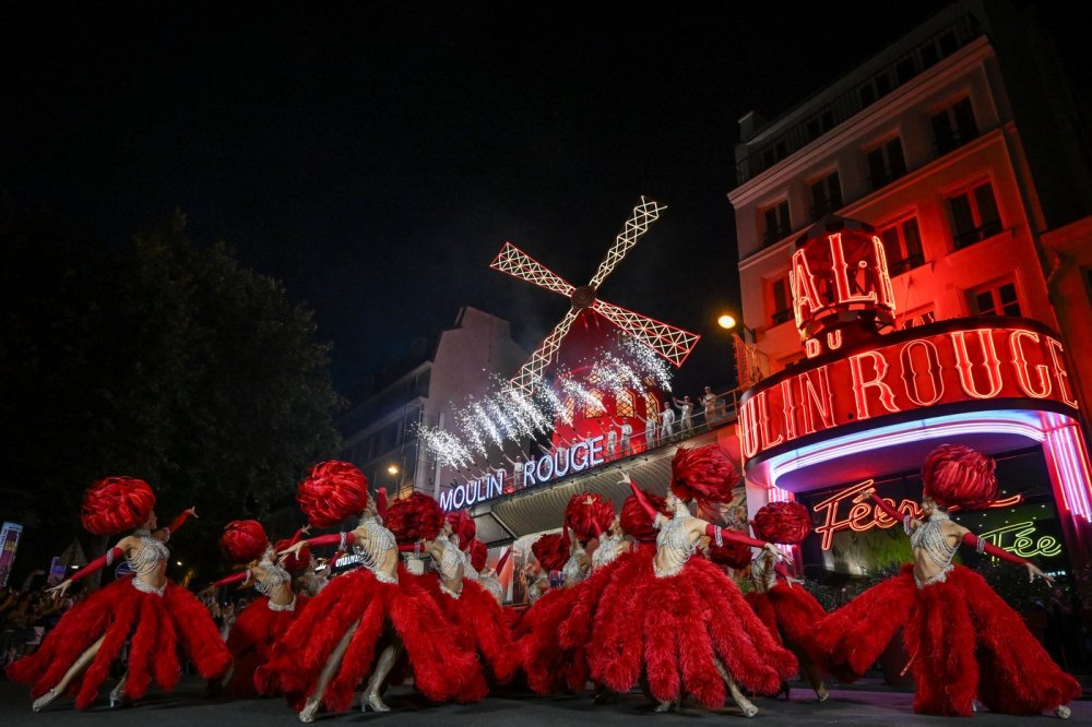 Lopatky červeného větrného mlýna na kabaretu Moulin Rouge v Paříži se roztočily ve čtvrtek večer. Událost oslavily desítky slavnostně oděných tanečnic před objektem tancem kankánu.