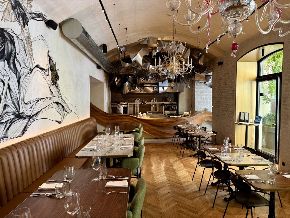Elegantní prostor restaurace s murálem a pohledem do otevřené kuchyně