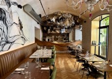 Elegantní prostor restaurace s murálem a pohledem do otevřené kuchyně