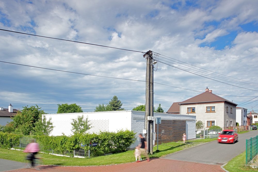 Po stranách jsou dva cihelné bloky, jeden se soukromou ložnicí otevřenou do atria se saunou, druhý s dětskými pokoji a kůlnou. Mezi nimi proplouvá denní život. Od ulice vstupním nádvořím se stromkem a krytým stáním kolem kuchyně a koupelen do obýváku s jídelnou až na terasu do zahrady.