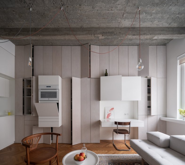 Celou jednu stěnu bytu tvoří bíle olejovaný dubový obklad skrývající úložné prostory. Je to pomyslná páteř, která drží byt pohromadě. Jejím protipólem je vzdušná konstrukce knihovny vyrobená z velmi subtilních ocelových profilů.