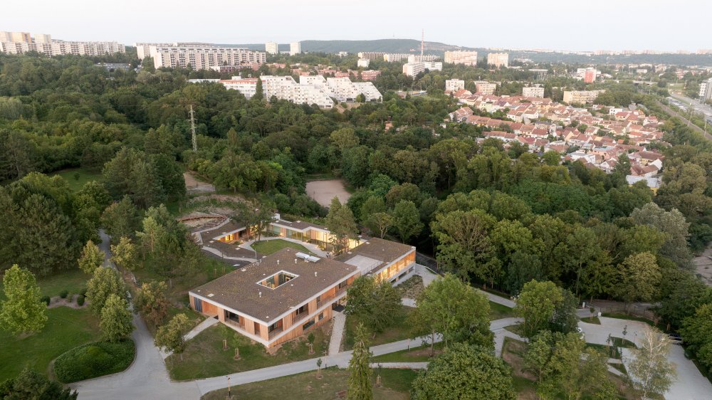 Dům pro Julii je i přes svou velikost docela nenápadný, citlivě zasazený do přírodního amfiteátru původního parku a otočený do chráněného vnitřního atria se zachovanými původními stromy.