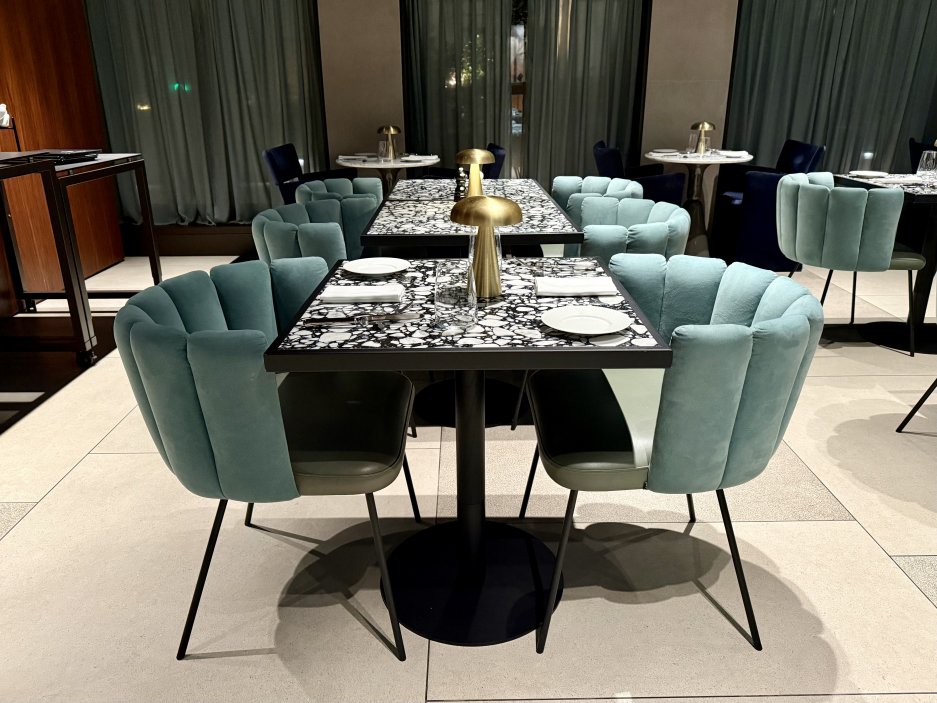 Interiér hotelové restaurace – sametové židle v odstínech moře a mramorové stolky působí elegantně i pohodlně