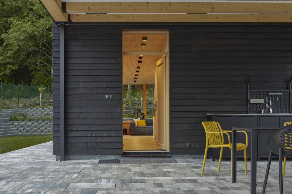 Rodinný dům v Kolíně pracuje s výrazným hmotovým kontrastem a ikonickou „odříznutou“ vyhlídkou v horním patře. Návrh vychází z archetypu domu se stodolou a jemně kombinuje rodinné bydlení s farmářským charakterem. Černá prkenná fasáda doplňuje světlý dřevěný interiér a celý dům je silně propojený s okolní krajinou a přírodou.