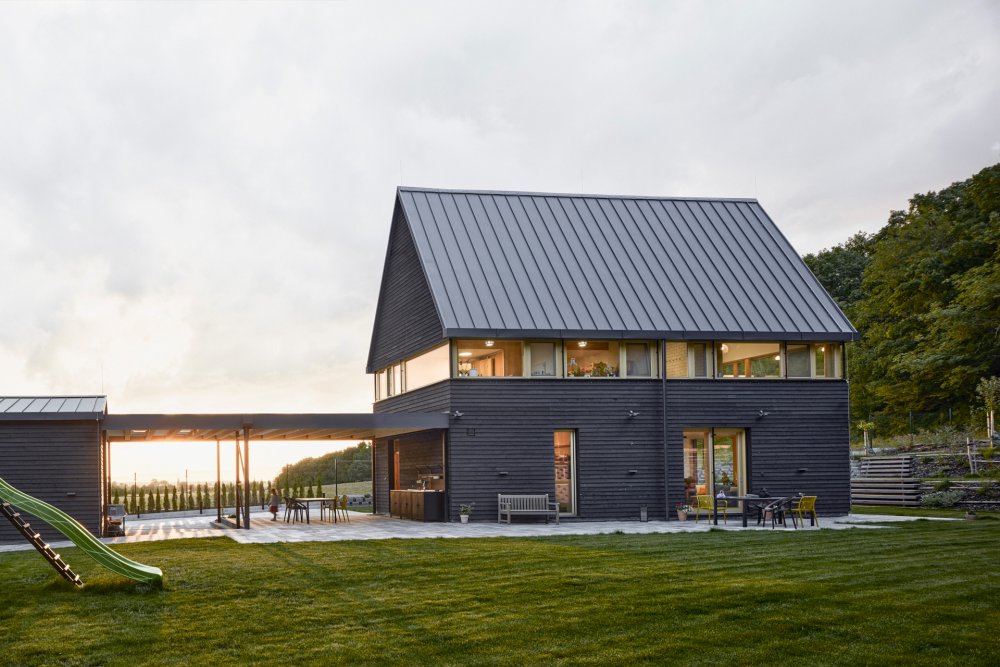 Rodinný dům v Kolíně pracuje s výrazným hmotovým kontrastem a ikonickou „odříznutou“ vyhlídkou v horním patře. Návrh vychází z archetypu domu se stodolou a jemně kombinuje rodinné bydlení s farmářským charakterem. Černá prkenná fasáda doplňuje světlý dřevěný interiér a celý dům je silně propojený s okolní krajinou a přírodou.