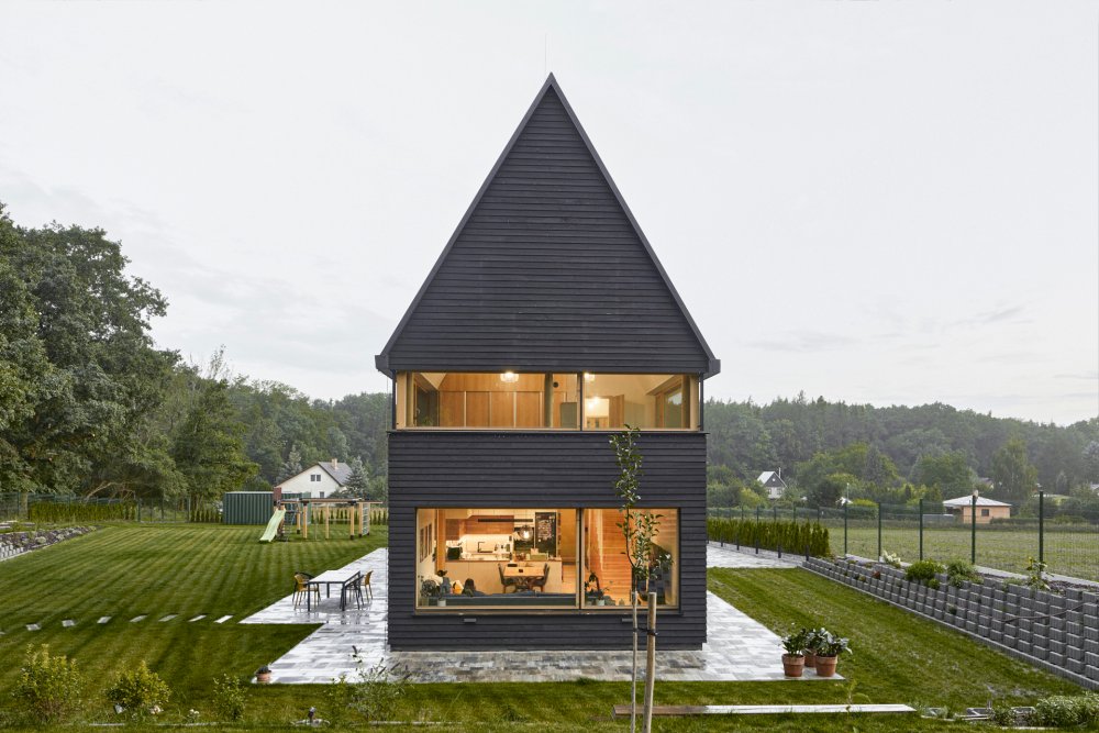 Rodinný dům v Kolíně pracuje s výrazným hmotovým kontrastem a ikonickou „odříznutou“ vyhlídkou v horním patře. Návrh vychází z archetypu domu se stodolou a jemně kombinuje rodinné bydlení s farmářským charakterem. Černá prkenná fasáda doplňuje světlý dřevěný interiér a celý dům je silně propojený s okolní krajinou a přírodou.