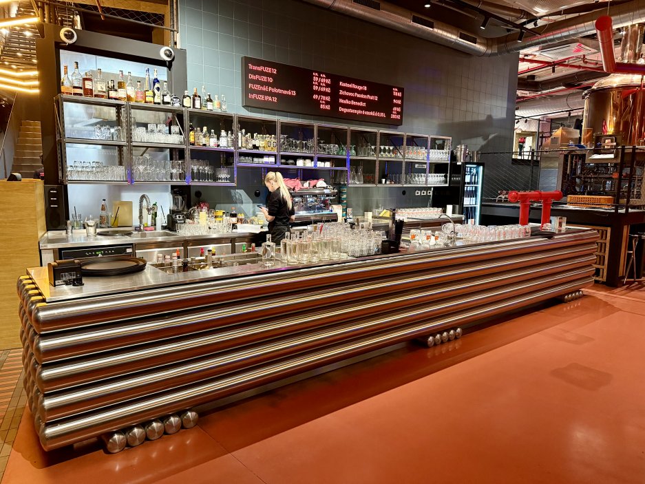Hlavní bar restaurace FUZE s industriálním designem a výčepem vlastních piv
