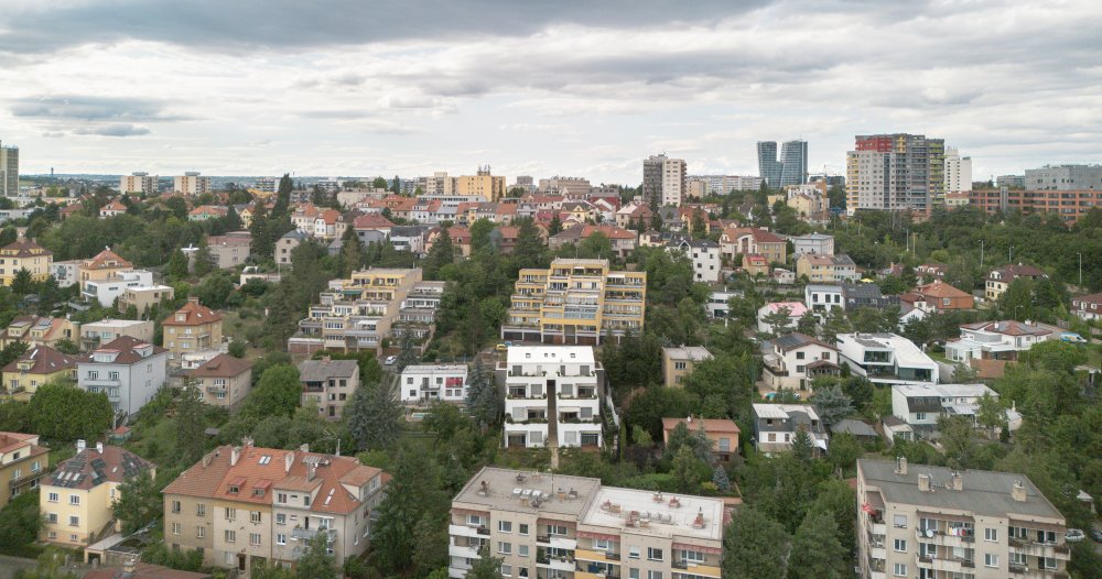 Výsledný dvojdům charakterizují terasy orientované na jih umožňující po svém obvodu výsadbu vyšší zeleně. Hmota je řešena jako ustupující bílý blok kopírující terén. Na bočních fasádách jsou dle výhledů z interiéru komponovány různé typy čtvercových oken. Na úrovni ulice je tento bílý monolit protnut horizontálním objemem garáží opláštěným přírodním hliníkovým falcovaným plechem.