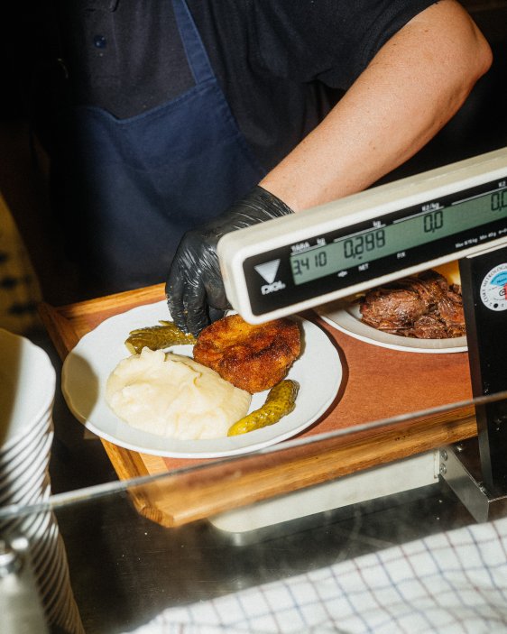 Při vstupu dostanete objednávací kartu, na kterou se u jednotlivých pultů zapisuje vše, co si vyberete. Platí se až při odchodu podle obsahu karty a váhy porcí. Jíst můžete vsedě u stolu nebo neformálně ve stoje u velkého společného stolu.