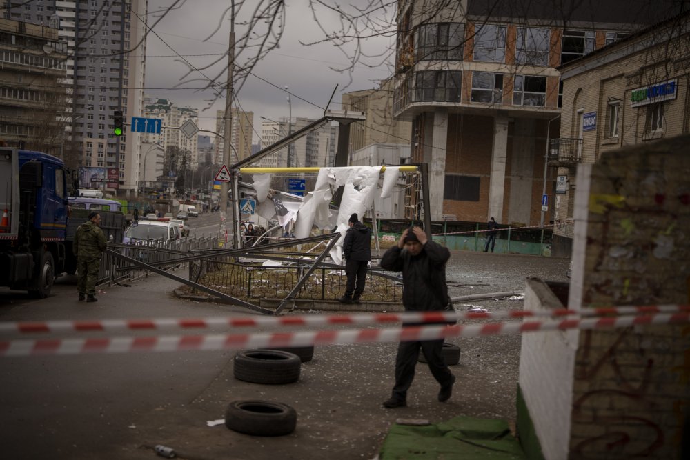 Policisté v Kyjevě hlídají místo poškozené po dopadu ruské rakety.
