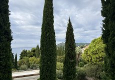 Výhled z hotelu na typickou dalmatskou krajinu s cypřiši a mořem v dálce 