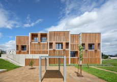 Konstrukce pavlačí je tvořena lepenými dřevěnými vazníky kotvenými do betonových jader, což umožňuje přesnou montáž a minimalizaci mokrých procesů.