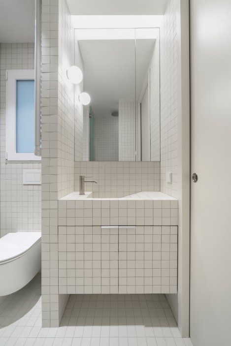 Malé porcelánové dlaždice sjednocují koupelnu i úložné prostory.