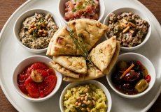 Mezze. Na talíř v tomto případě dostanete několik mističek s tataráčkem z lososa a tuňáka, pečenými paprikami, bílými fazolemi, marinovanými olivami a pečeným lilkem s jogurtem.