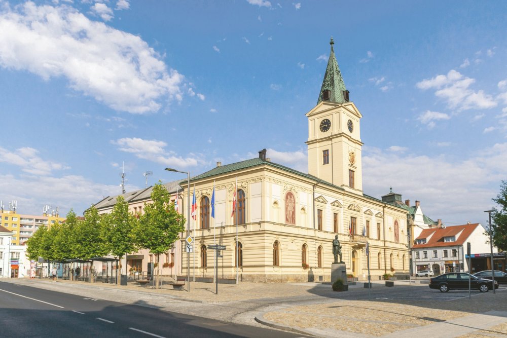 Křížící se linie v dlažbě, inspirované symboly města, dávají náměstí jasný řád a pomáhají přirozeně organizovat pohyb chodců, cyklistů i dopravy.