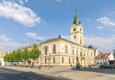 Křížící se linie v dlažbě, inspirované symboly města, dávají náměstí jasný řád a pomáhají přirozeně organizovat pohyb chodců, cyklistů i dopravy.
