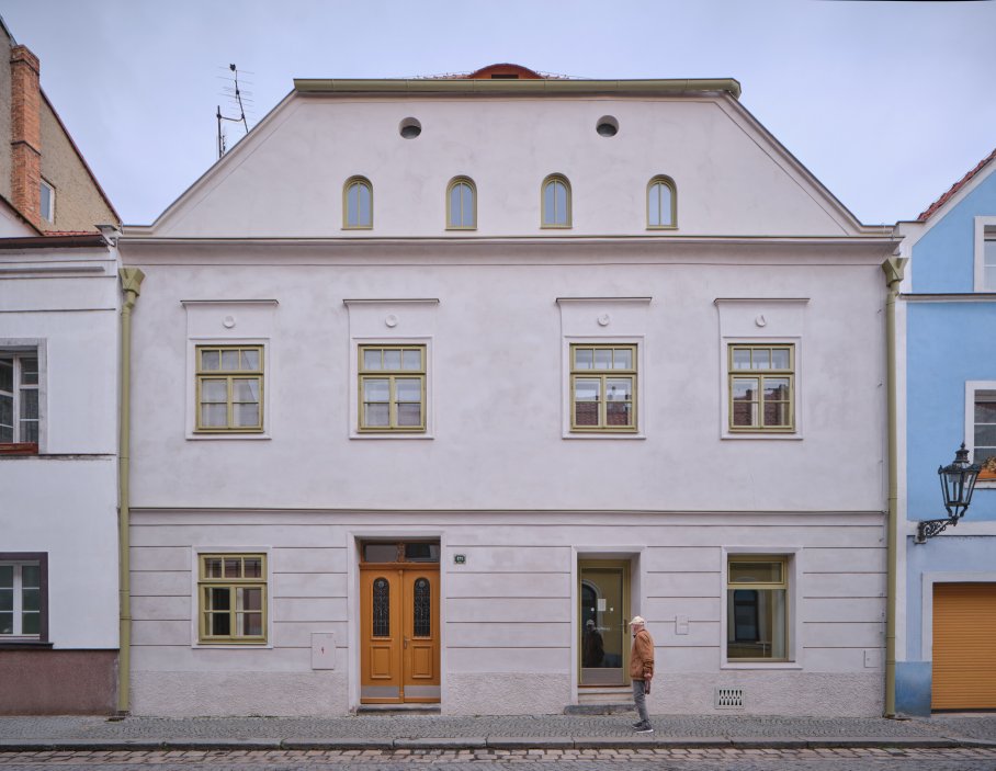 Architekti Jan a Barbora Horovi ze studia ORA proměnili rodinný dům v žatecké Obloukové ulici z téměř ztracené ruiny v místo, kde se potkává ubytování, výčep a soukromé zázemí. Rekonstrukce trvala osm let a stála na snaze zachovat maximum původních konstrukcí, využít recyklované materiály a nechat starý dům stárnout dál — jen s novým životem.
