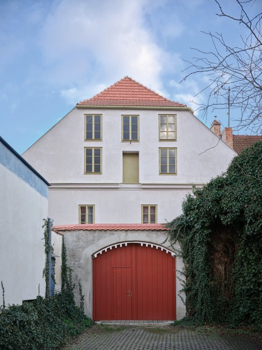 Architekti Jan a Barbora Horovi ze studia ORA proměnili rodinný dům v žatecké Obloukové ulici z téměř ztracené ruiny v místo, kde se potkává ubytování, výčep a soukromé zázemí. Rekonstrukce trvala osm let a stála na snaze zachovat maximum původních konstrukcí, využít recyklované materiály a nechat starý dům stárnout dál — jen s novým životem.