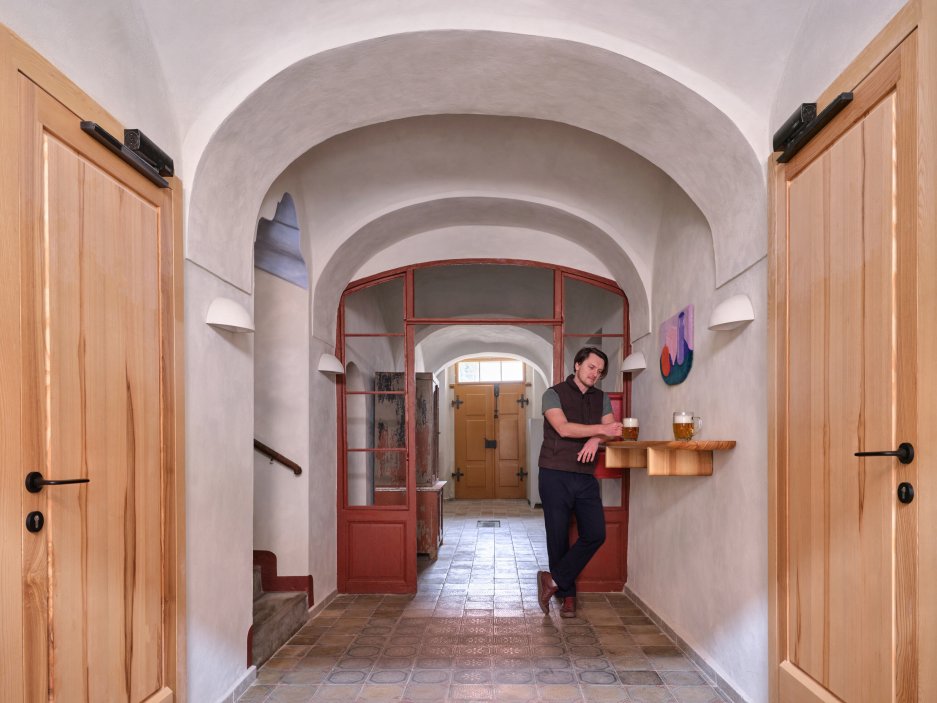 Architekti Jan a Barbora Horovi ze studia ORA proměnili rodinný dům v žatecké Obloukové ulici z téměř ztracené ruiny v místo, kde se potkává ubytování, výčep a soukromé zázemí. Rekonstrukce trvala osm let a stála na snaze zachovat maximum původních konstrukcí, využít recyklované materiály a nechat starý dům stárnout dál — jen s novým životem.