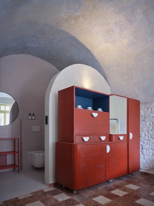 Architekti Jan a Barbora Horovi ze studia ORA proměnili rodinný dům v žatecké Obloukové ulici z téměř ztracené ruiny v místo, kde se potkává ubytování, výčep a soukromé zázemí. Rekonstrukce trvala osm let a stála na snaze zachovat maximum původních konstrukcí, využít recyklované materiály a nechat starý dům stárnout dál — jen s novým životem.