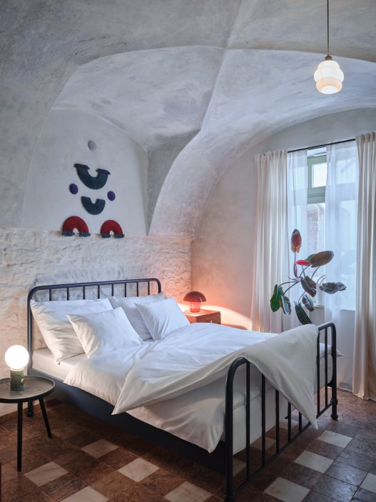 Architekti Jan a Barbora Horovi ze studia ORA proměnili rodinný dům v žatecké Obloukové ulici z téměř ztracené ruiny v místo, kde se potkává ubytování, výčep a soukromé zázemí. Rekonstrukce trvala osm let a stála na snaze zachovat maximum původních konstrukcí, využít recyklované materiály a nechat starý dům stárnout dál — jen s novým životem.