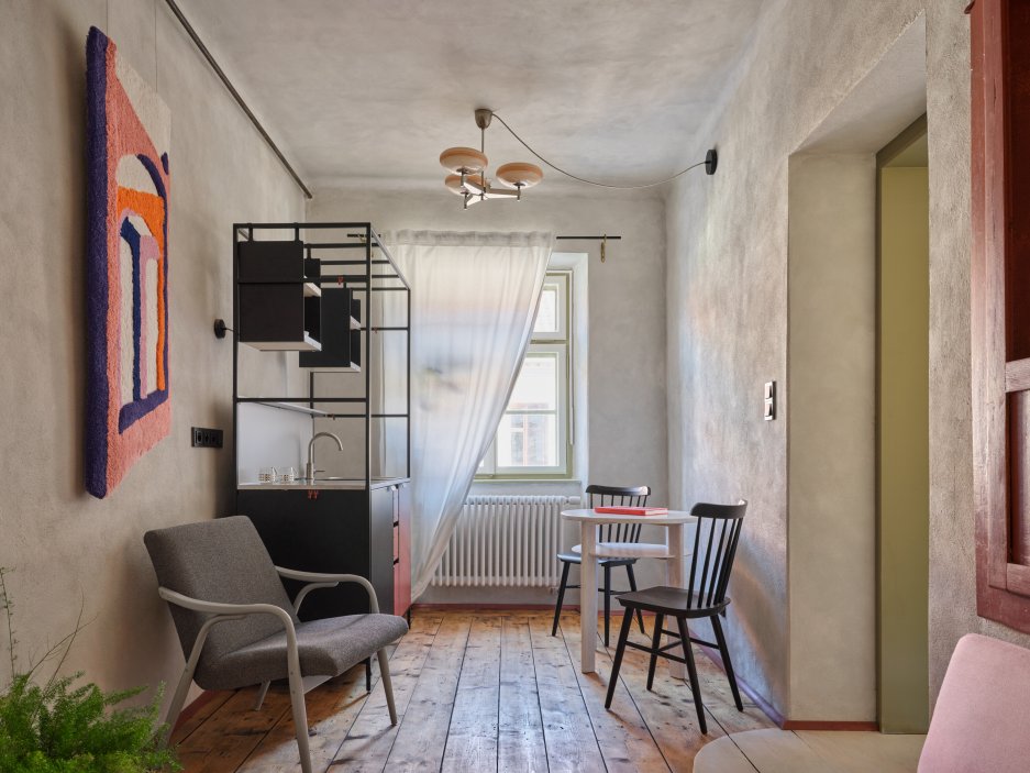 Architekti Jan a Barbora Horovi ze studia ORA proměnili rodinný dům v žatecké Obloukové ulici z téměř ztracené ruiny v místo, kde se potkává ubytování, výčep a soukromé zázemí. Rekonstrukce trvala osm let a stála na snaze zachovat maximum původních konstrukcí, využít recyklované materiály a nechat starý dům stárnout dál — jen s novým životem.